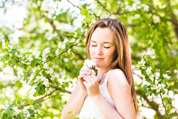 Romantica giovane donna con gli occhi chiusi nel giardino primaverile tra i fiori di melo, soft focus — Foto Stock