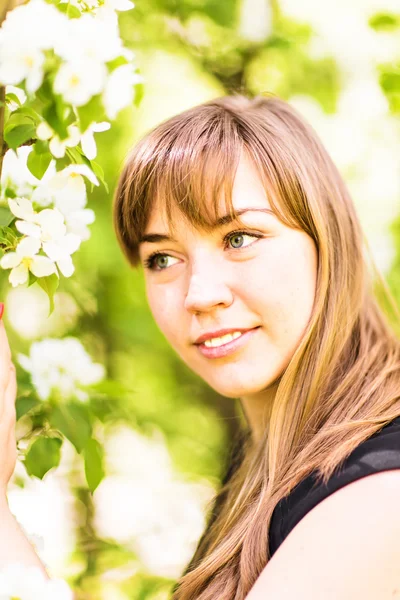 Belle jeune femme sur un arbre à fleurs blanches, portrait extérieur — Photo