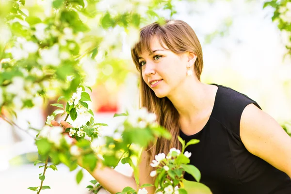 Belle jeune femme sur un arbre à fleurs blanches, portrait extérieur — Photo