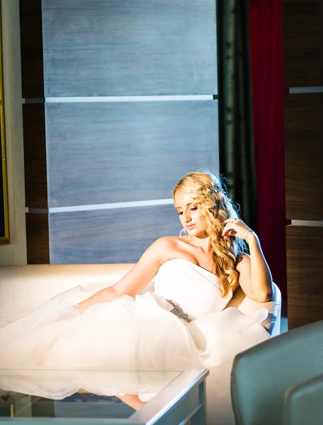 Blonde bruid zittend op de stoel in de kamer — Stockfoto