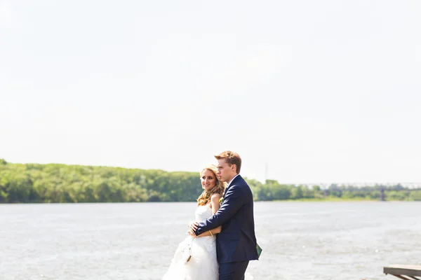 Mooie bruid en bruidegom door een meer of rivier — Stockfoto