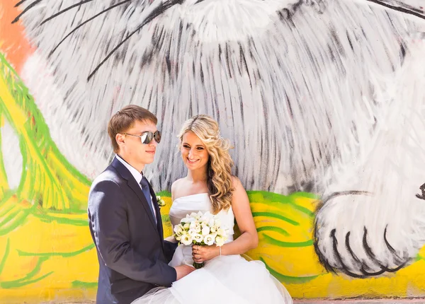 Наречений і наречений обіймаються на фоні графіті стіни — стокове фото