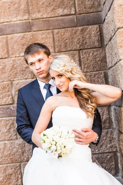 Bruden och brudgummen nära väggen — Stockfoto