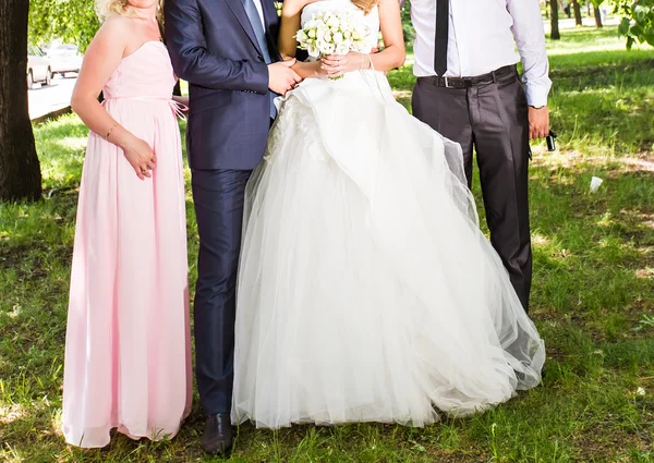 Счастливая невеста и жених стоят с гостями в саду — стоковое фото