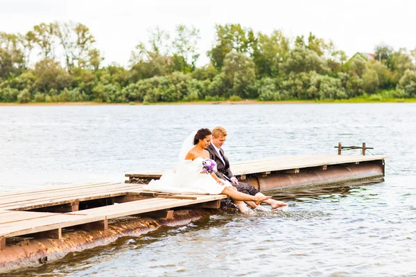 Mooie bruid en bruidegom door een meer of rivier — Stockfoto