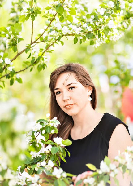 Hermosa mujer joven sobre el árbol de flor blanca, retrato al aire libre — Foto de Stock