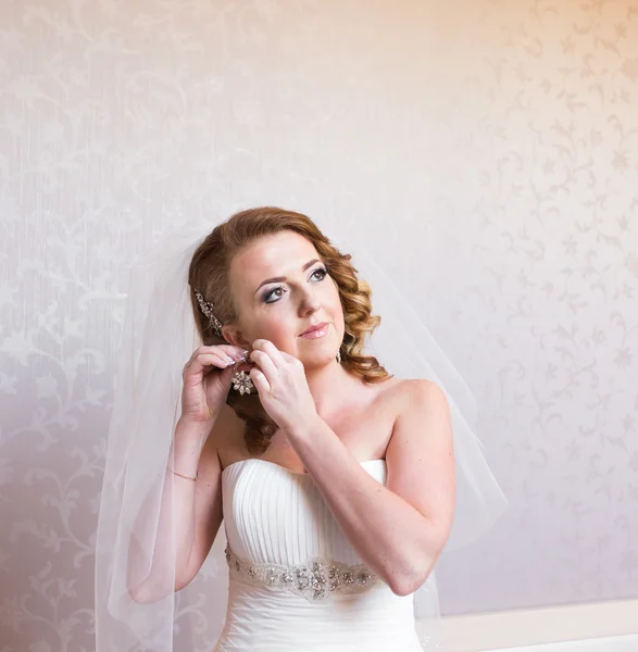 Bruid zichzelf zet haar oorbellen op de oren — Stockfoto