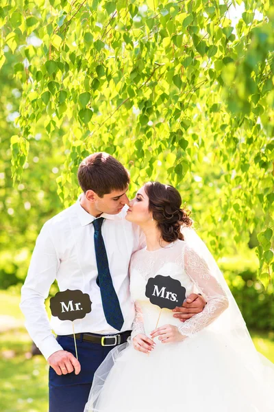 Noiva e noivo engraçados com os sinais do Sr. e da Sra.. Feliz dia do casamento — Fotografia de Stock