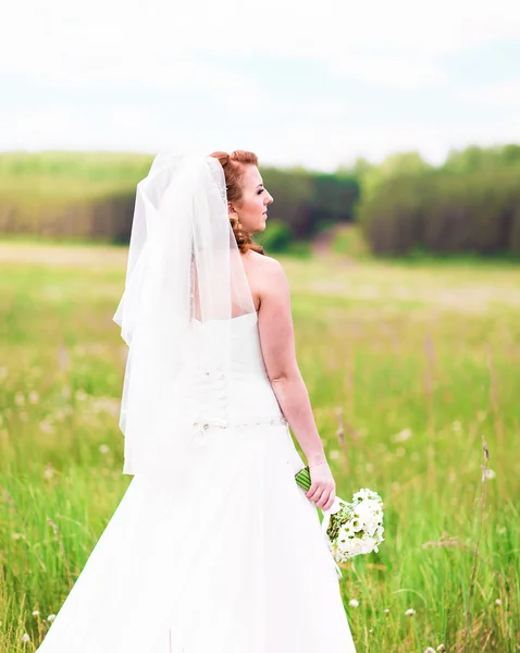 Bela noiva com buquê de casamento de flores ao ar livre no campo — Fotografia de Stock