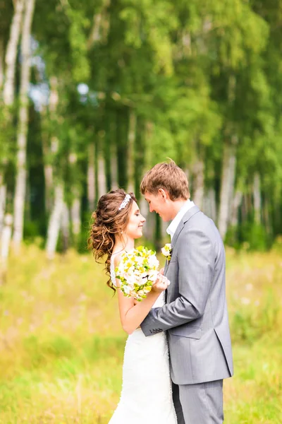 Schönes Hochzeitspaar im Park. sie küssen und umarmen sich — Stockfoto