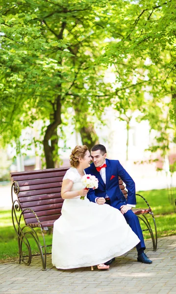 Счастливая невеста и жених сидят на лавочке — стоковое фото
