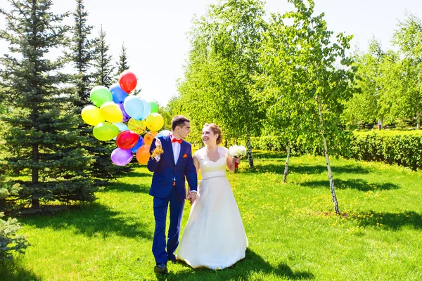 Belle mariée et marié sur un parc avec des ballons colorés — Photo