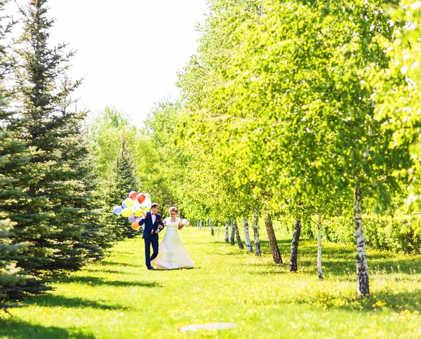 Пара жениха и невесты с шариками. Молодожены с воздушными шарами на открытом воздухе — стоковое фото