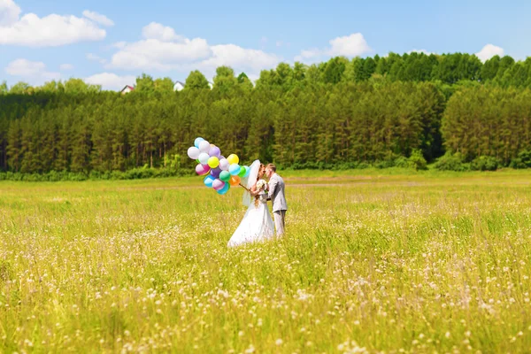 Hermosa novia sosteniendo un montón de globos en el parque. Un par de novios con globos. Recién casados con globos al aire libre —  Fotos de Stock