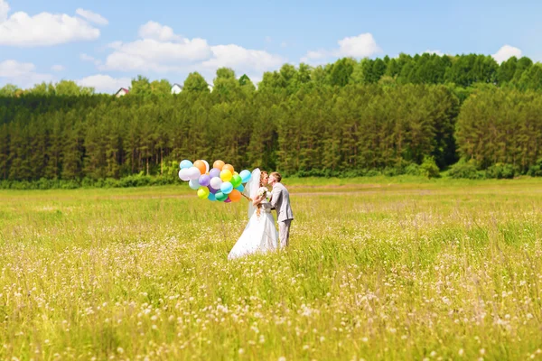 Belle mariée et marié sur une prairie avec des ballons colorés — Photo