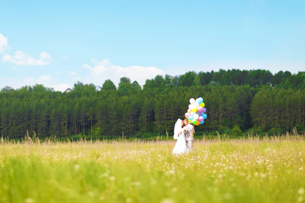 Belle mariée tenant un tas de ballons dans le parc. Couple de mariés avec des ballons. Jeunes mariés avec des ballons à l'extérieur — Photo