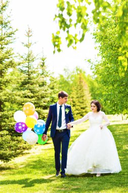 Gelin ve damat, düğün günü açık havada yürüyüş Doğa bahar. mutlu yeni evli kadın ve erkek yeşil park kucaklayan gelin çift. sevgi dolu evlilik çift açık