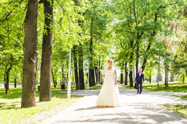 Bahçe, gelin ve damat fon karşı elinde iki sonra düğün kıyafetleri ile bir buket çiçek ve yeşillik olduğunu