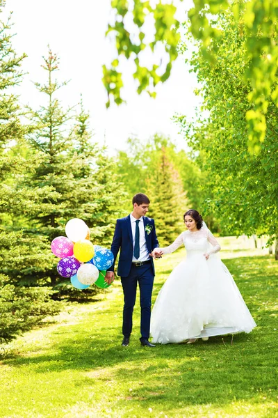 Menyasszony és a vőlegény az esküvő napján a szabadban séta tavasz természet. Nászutas pár, boldog newlywed nő és férfi átfogó zöld parkban. szerető esküvői pár kültéri — Stock Fotó