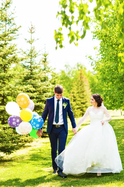 Beautiful bride and groom with colorful balloons — Stock Photo, Image