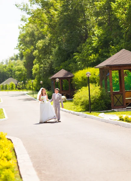 Novia y novio en el día de la boda caminando al aire libre en la naturaleza de primavera. Pareja nupcial, feliz mujer recién casada y hombre abrazándose en el parque verde. Amar pareja de boda al aire libre —  Fotos de Stock