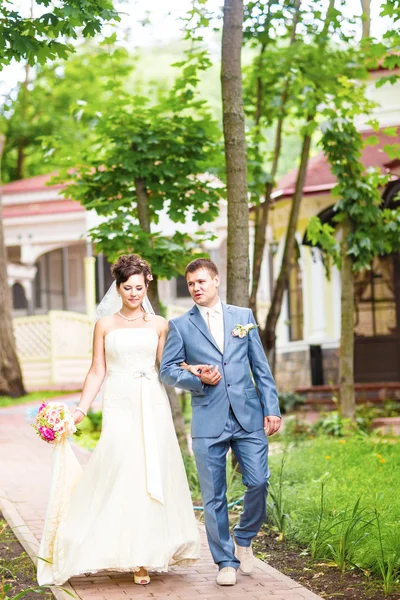 Braut und Bräutigam am Hochzeitstag beim Spaziergang in der Natur des Frühlings. Brautpaar, glückliche frisch vermählte Frau und Mann umarmen sich im grünen Park. Liebendes Hochzeitspaar im Freien — Stockfoto