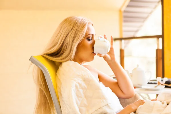 Linda jovem bebendo seu café da manhã, sentada na cadeira e olhando pela janela. Conceito matutino e acordado — Fotografia de Stock