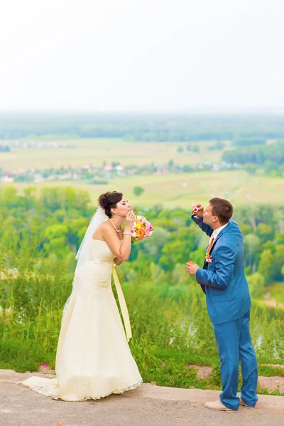 Beautiful wedding couple blowing bubbles — Stock Photo, Image