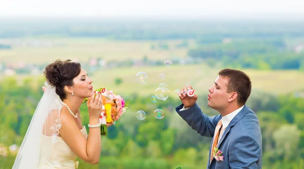 Beau couple de mariage soufflant bulles — Photo