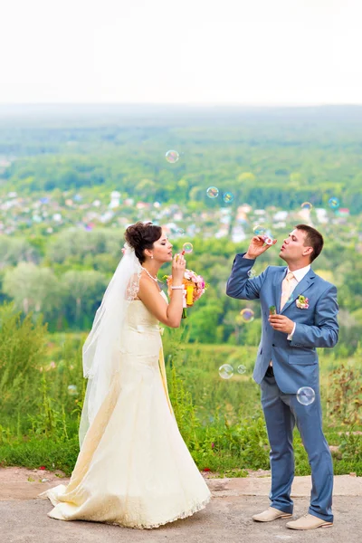 Beautiful wedding couple blowing bubbles — Stock Photo, Image