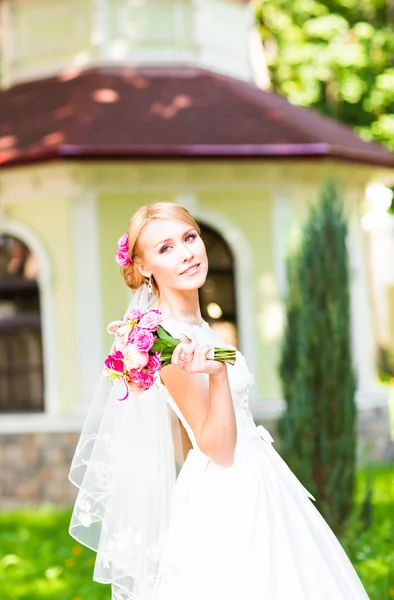 Vackra brud med bröllop bukett blommor utomhus i grön park — Stockfoto