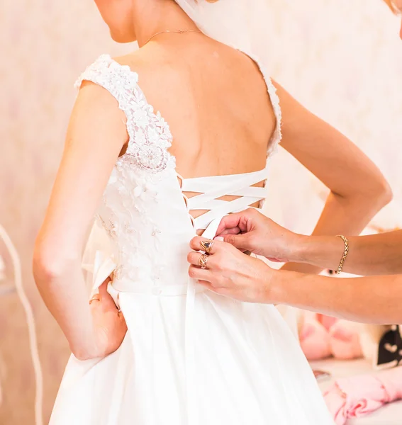 Bridesmaid tying bow on wedding dress — Stock Photo, Image