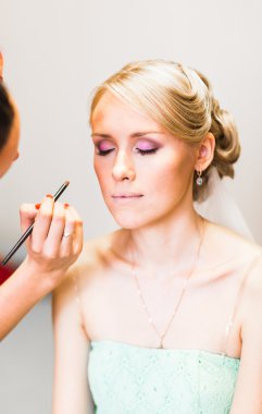 stylist maakt make-up bruid op de huwelijksdag