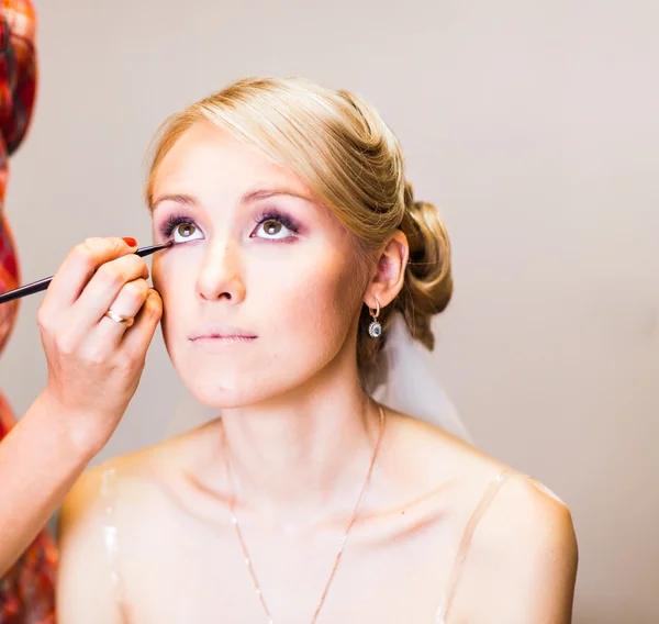 Maquillaje artista haciendo maquillaje para la novia hermosa joven aplicando maquillaje de boda — Foto de Stock