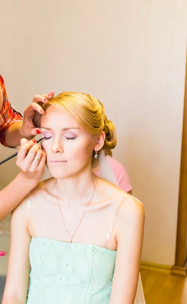 Maquillaje artista haciendo maquillaje para la novia hermosa joven aplicando maquillaje de boda — Foto de Stock