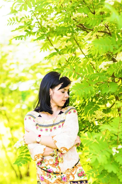 Mulher bonita de pé em um parque na primavera ou verão — Fotografia de Stock