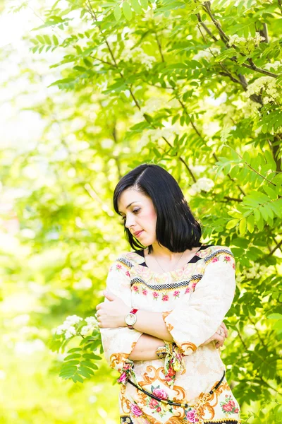 Mulher bonita de pé em um parque na primavera ou verão — Fotografia de Stock