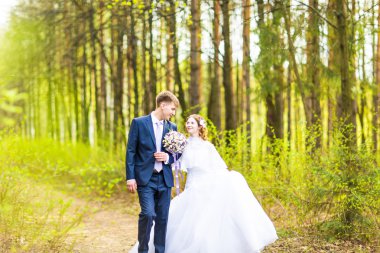 Gelin ve damat, düğün günü açık havada yürüyüş Doğa bahar. mutlu yeni evli kadın ve erkek yeşil park kucaklayan gelin çift. sevgi dolu evlilik çift açık.