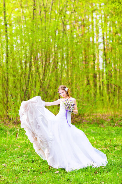 Bride wedding dress develops in the air against green field