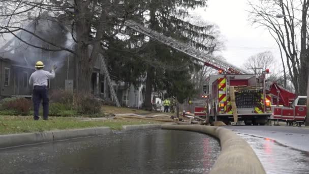 Bomberos apagan una casa en llamas — Vídeo de stock