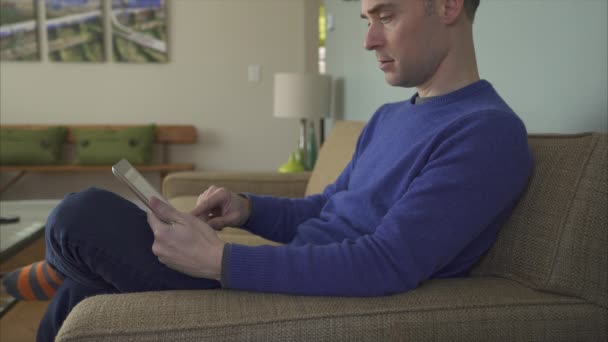 Uomo su un divano utilizzando le ultime tecnologie — Video Stock
