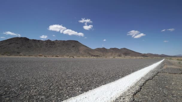 Χτυπήματα Tumbleweed πέρα από ένα δρόμο στην έρημο — Αρχείο Βίντεο