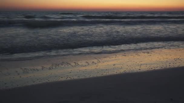 Uma vista do pôr do sol de ondas suavemente lavando ao longo da praia — Vídeo de Stock