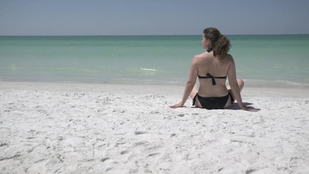 Een vrouw ligt op het strand bij een resort — Stockvideo