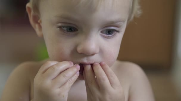 Een kind geniet van een hapje terwijl u zit op de eettafel kamer — Stockvideo