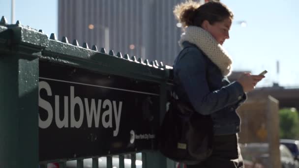 Μια όμορφη νεαρή γυναίκα βρίσκεται σε μια ηλιόλουστη ημέρα κοντά σε ένα σταθμό του μετρό — Αρχείο Βίντεο