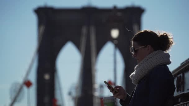 Güzel bir genç kadın güneşli bir Brooklyn Köprüsü üzerinde sahiptir. — Stok video