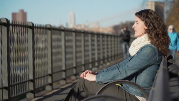 Uma bela mulher perto da Ponte Brooklyn olha para Manhattan — Vídeo de Stock