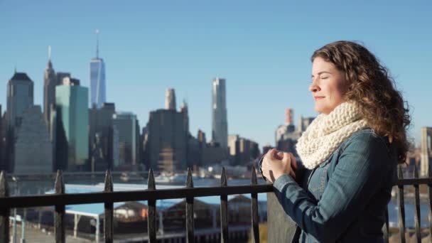 Uma bela mulher perto da Ponte Brooklyn olha para Manhattan — Vídeo de Stock