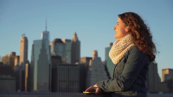 Uma bela mulher perto da Ponte Brooklyn olha para Manhattan — Vídeo de Stock